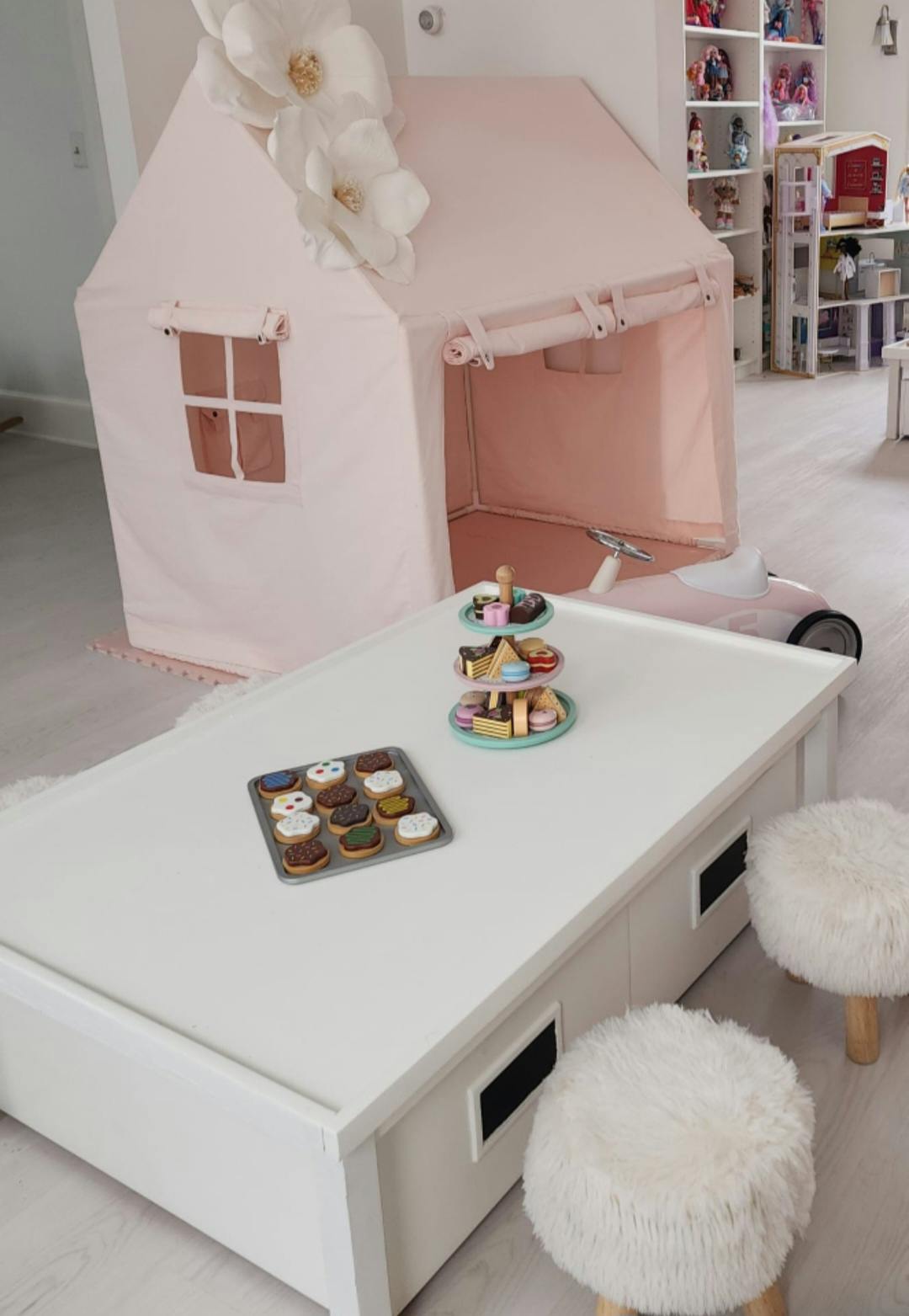 Playroom with a pink tent, white table, and toy desserts
