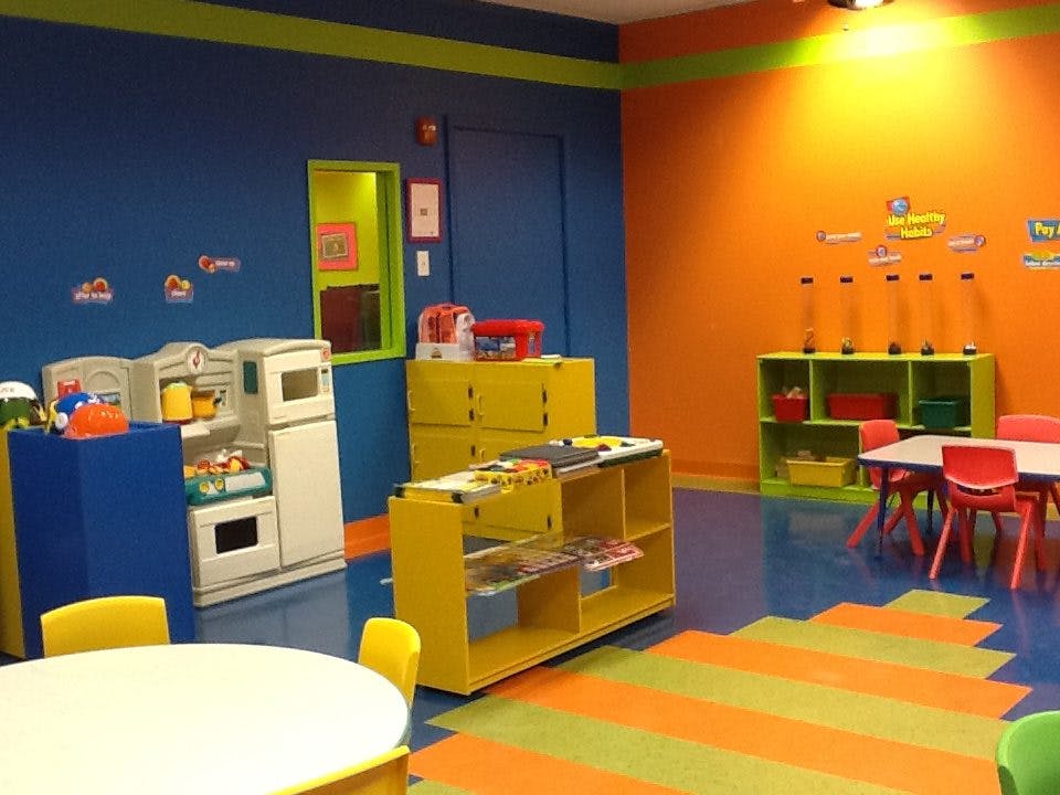 Playroom with blue and orange walls, toy kitchen, and small tables