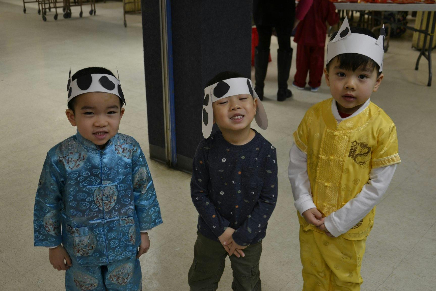 Three children wearing animal-themed hats and traditional clothing