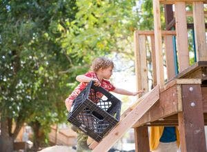 Child holding a crate climbing wooden stairs
