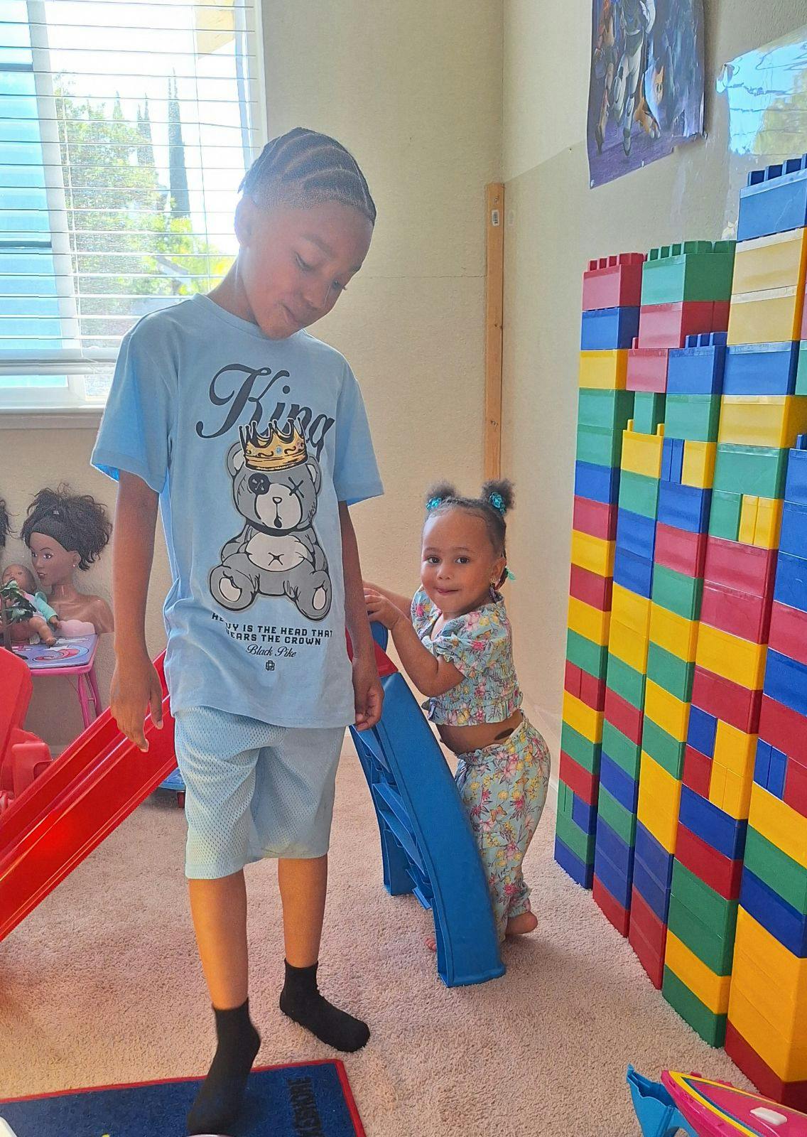 Child and toddler playing with large building blocks and a slide