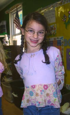 Child with glasses and braided hair smiling