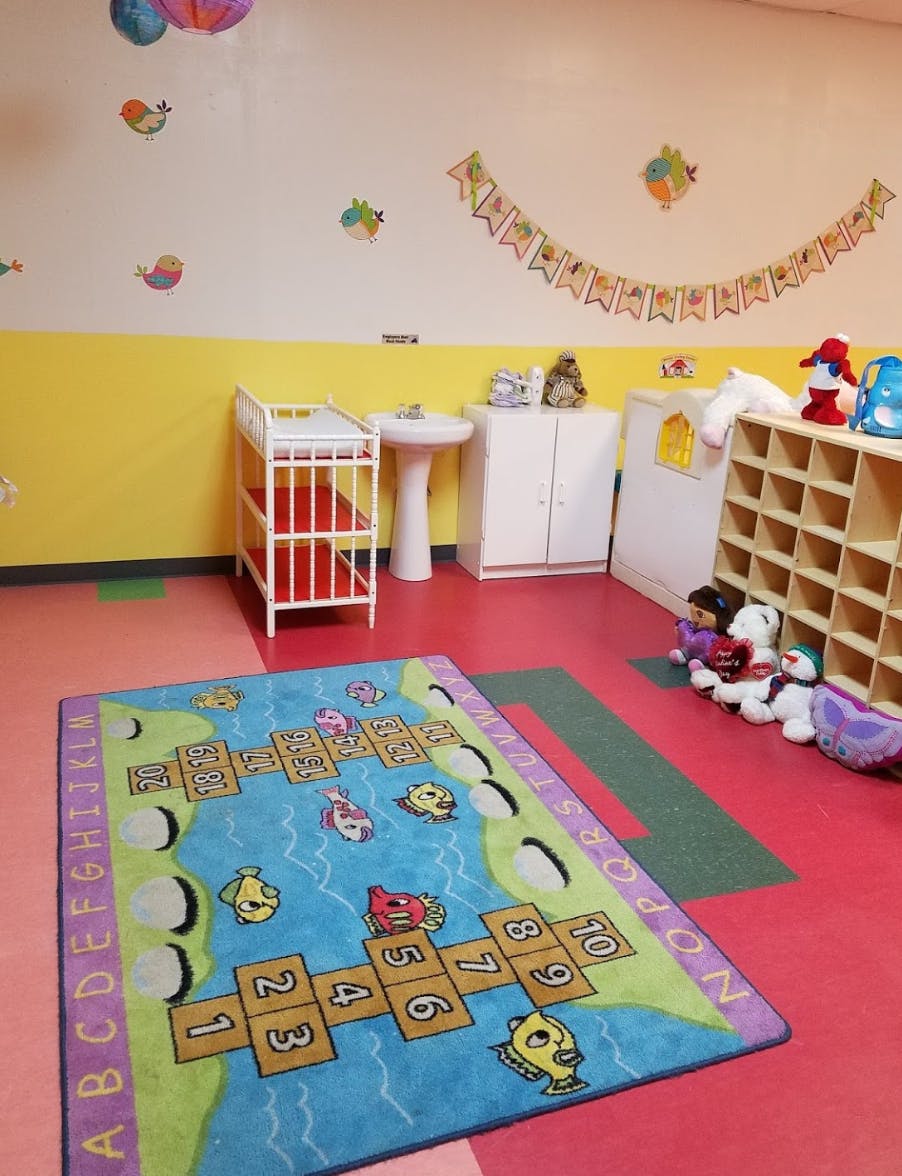 Playroom with a colorful rug, crib, and sink