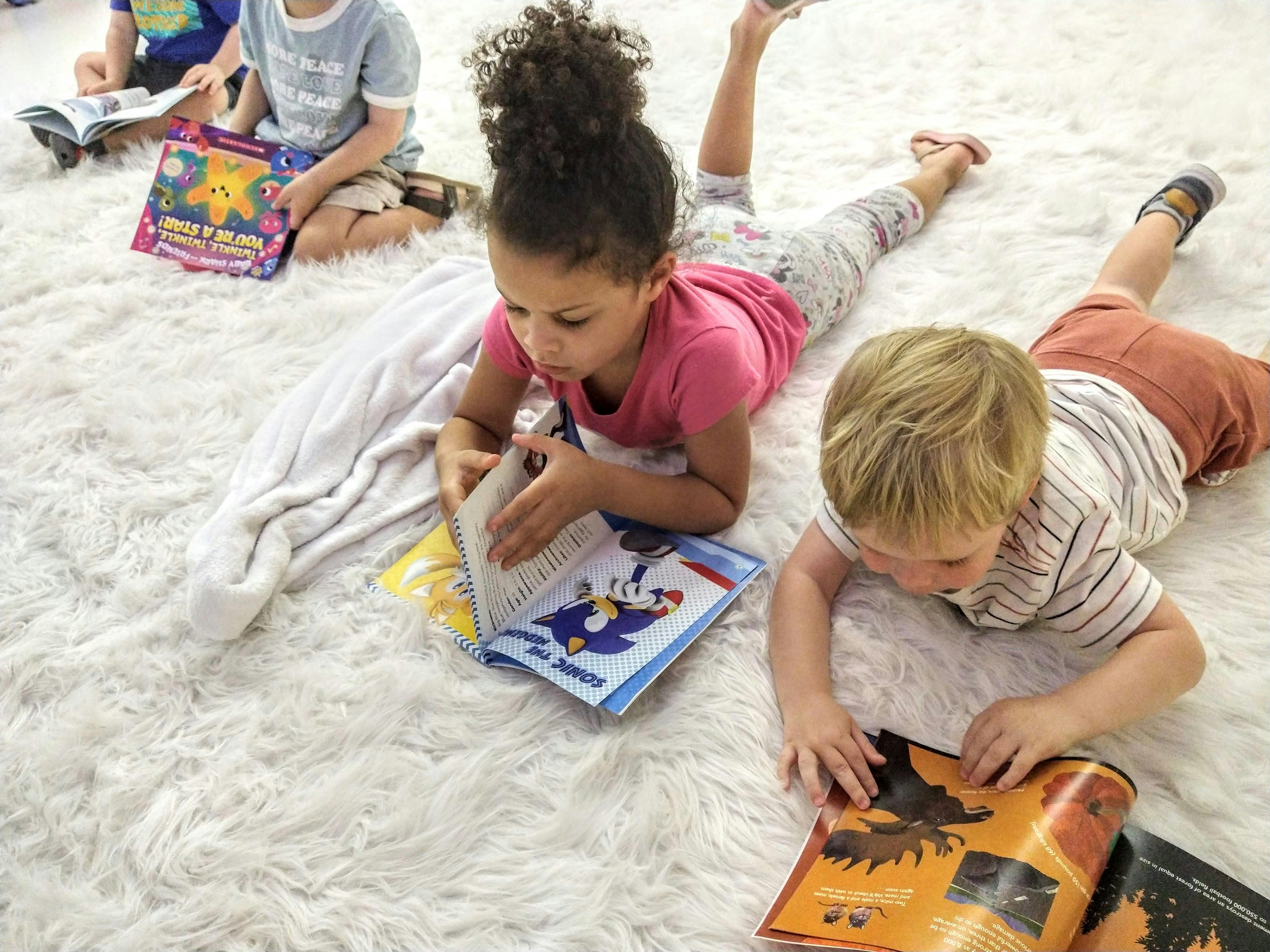 Children lying on a rug reading books