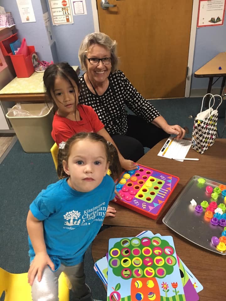 Adult and two children at a table with colorful games