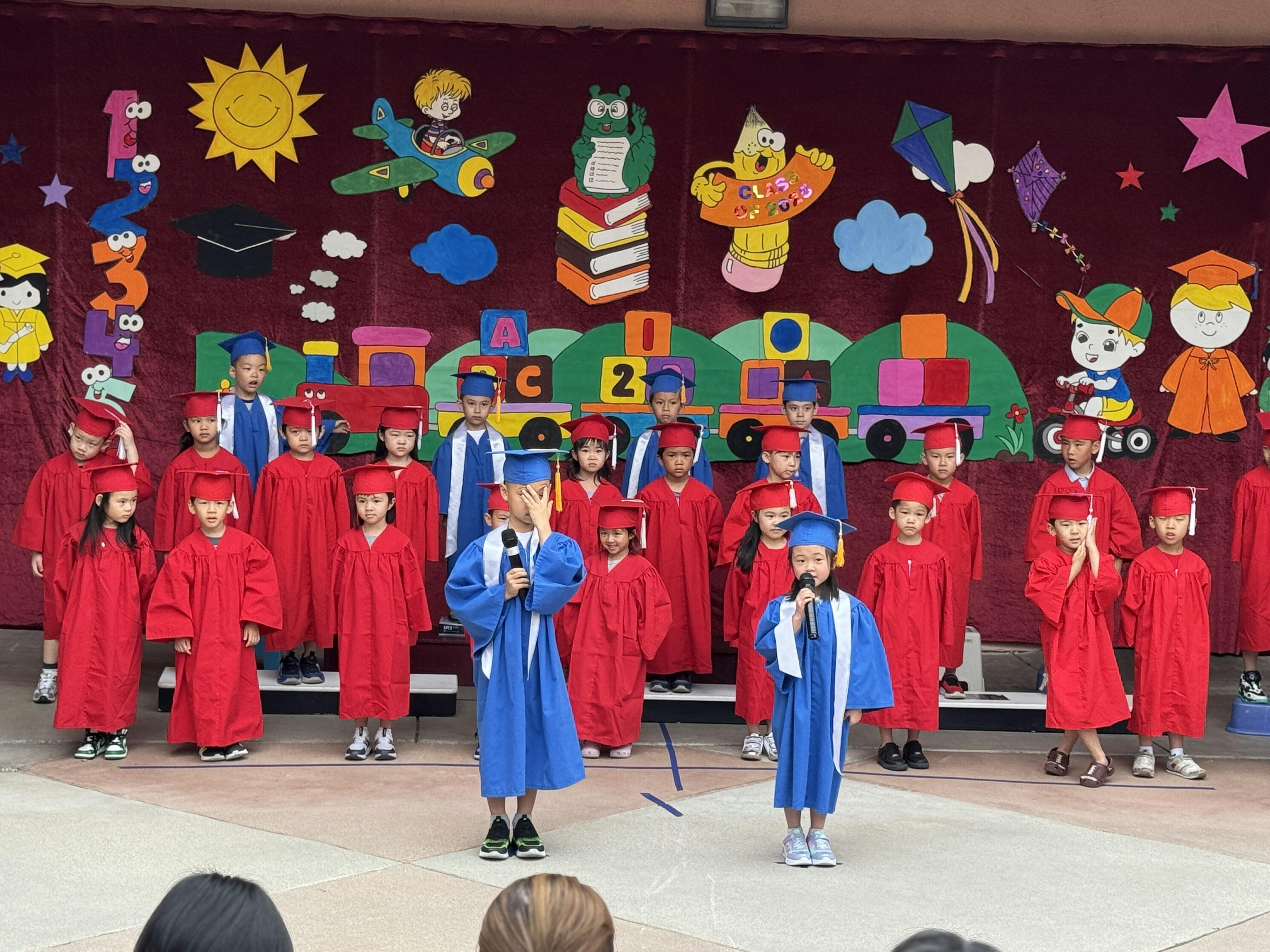 Children in graduation gowns and caps on a stage