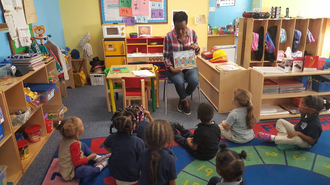 Person reading a book to children in a classroom