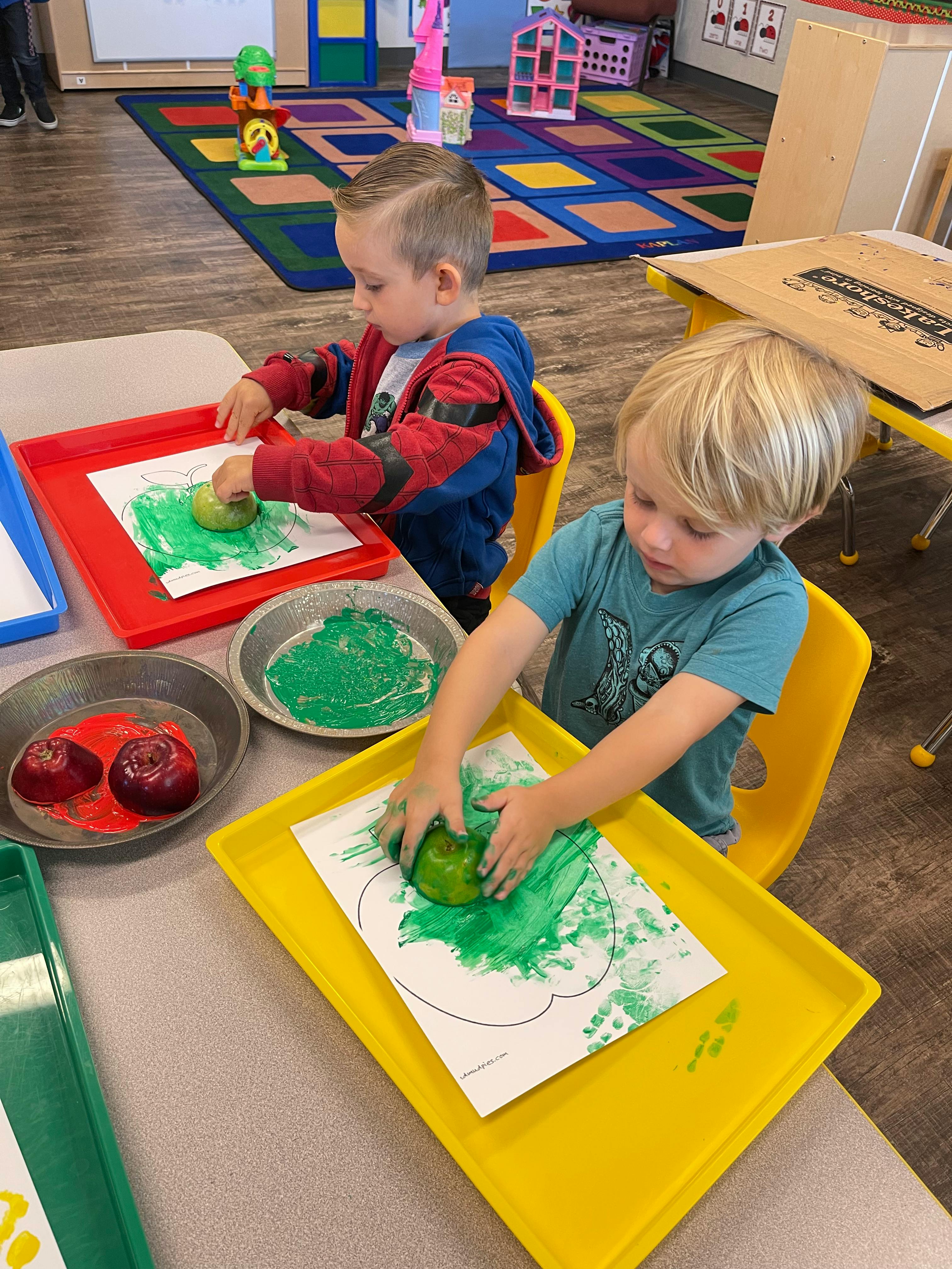Two children doing apple stamping art
