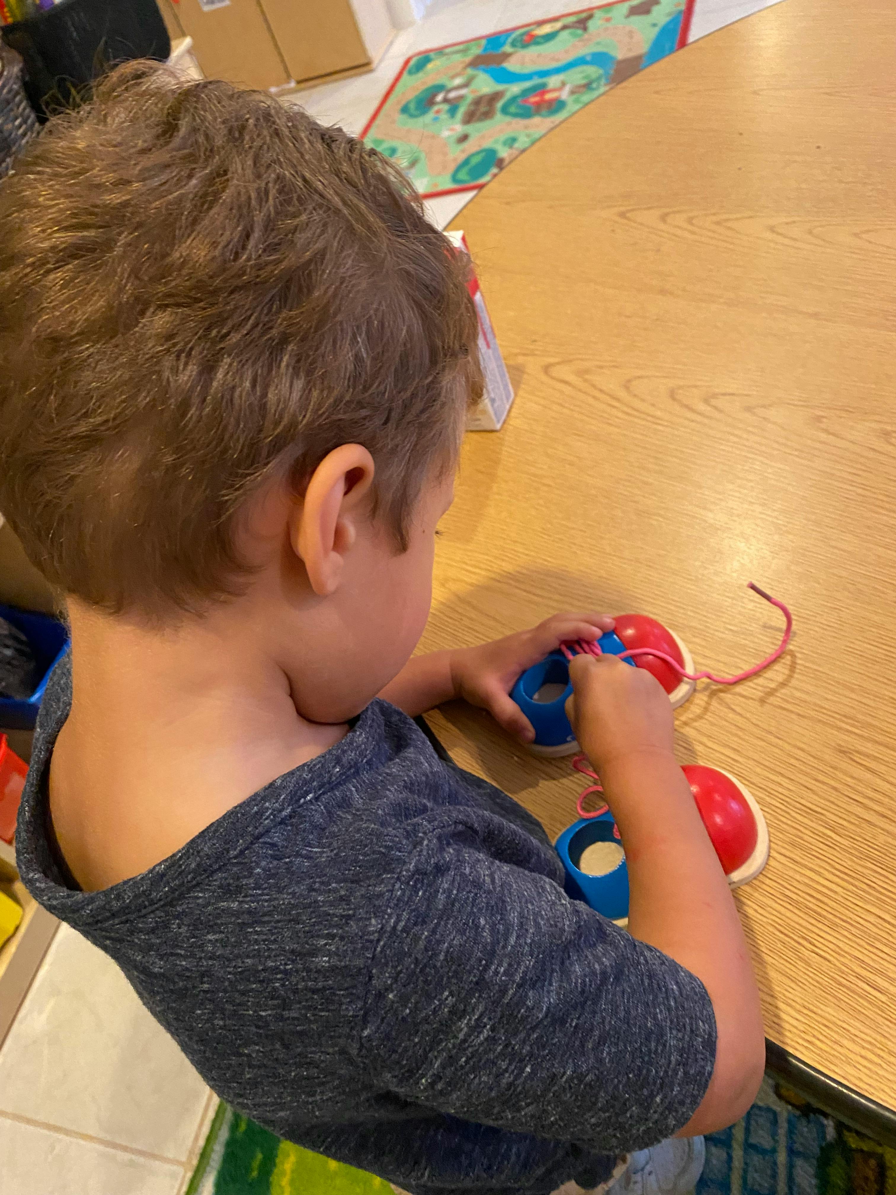 Child playing with a lacing toy at a table
