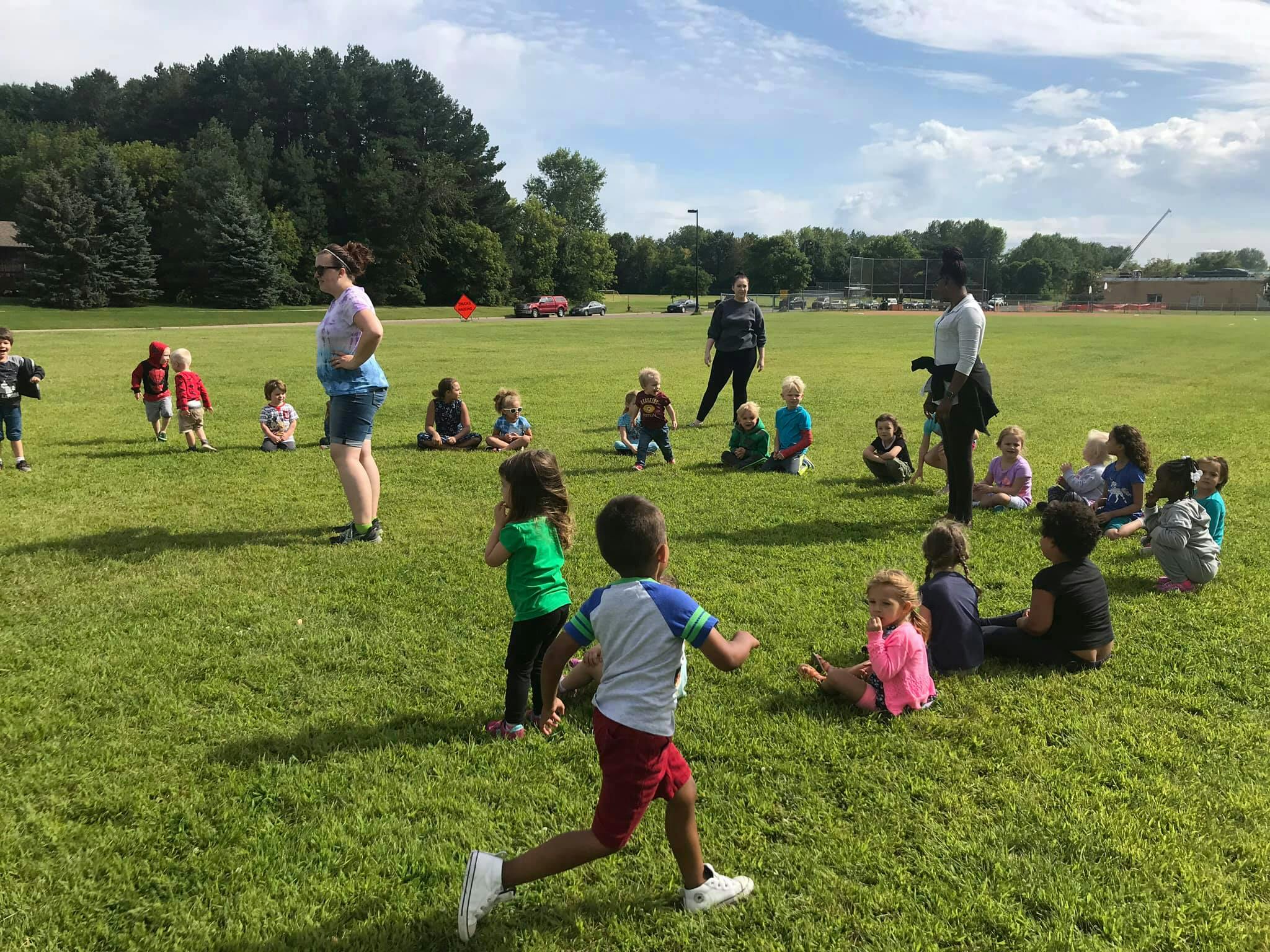 Adults and children playing in a grassy field