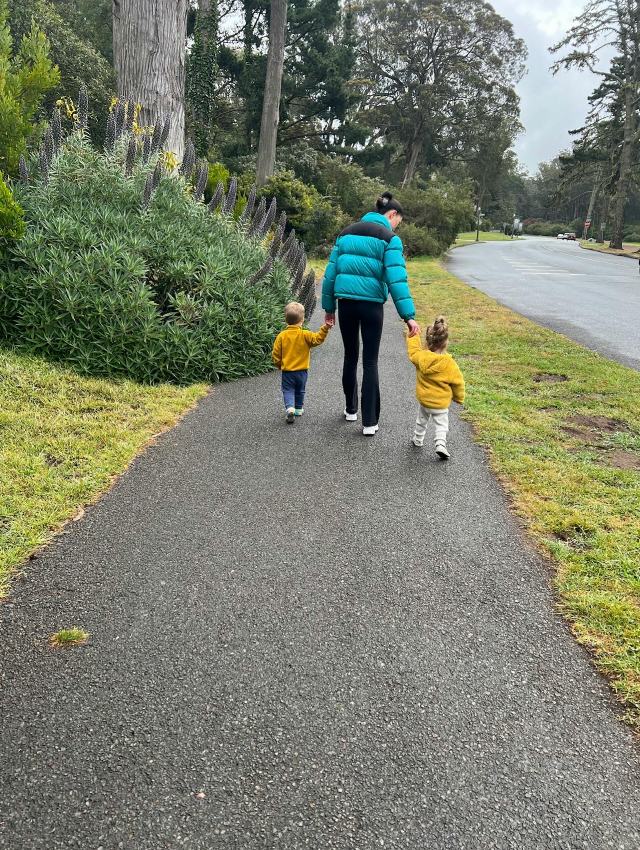 Person walking with two children on a paved path