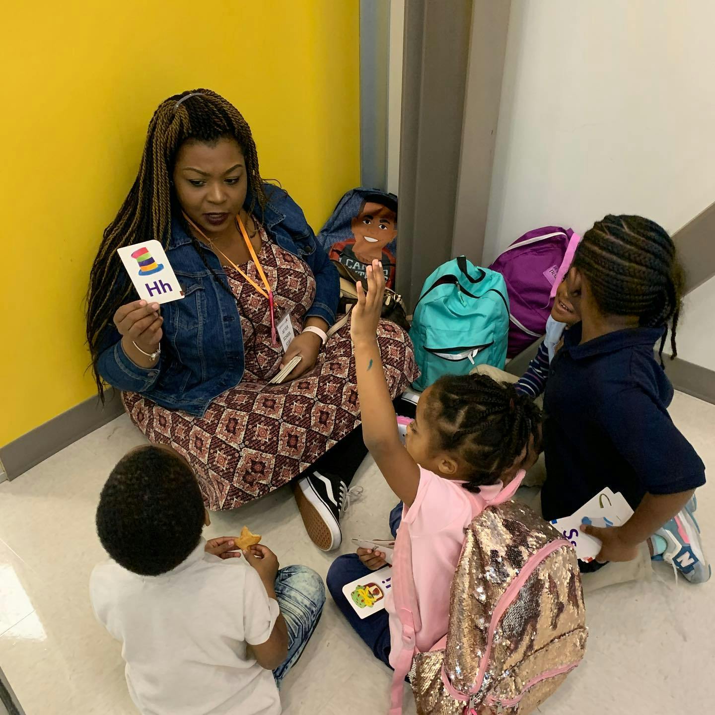 Person holding up a flashcard with "Hh" to children