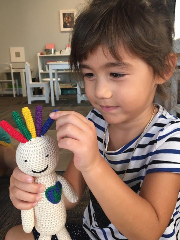 Child playing with a crocheted doll with colorful hair