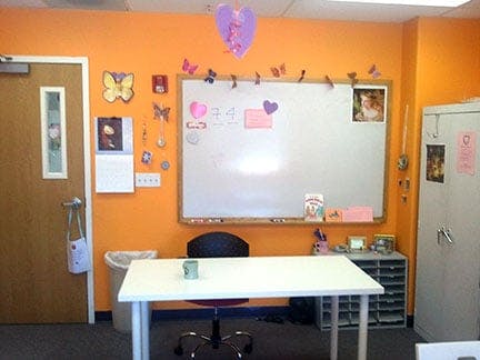 Classroom with orange walls, whiteboard, desk, and chair