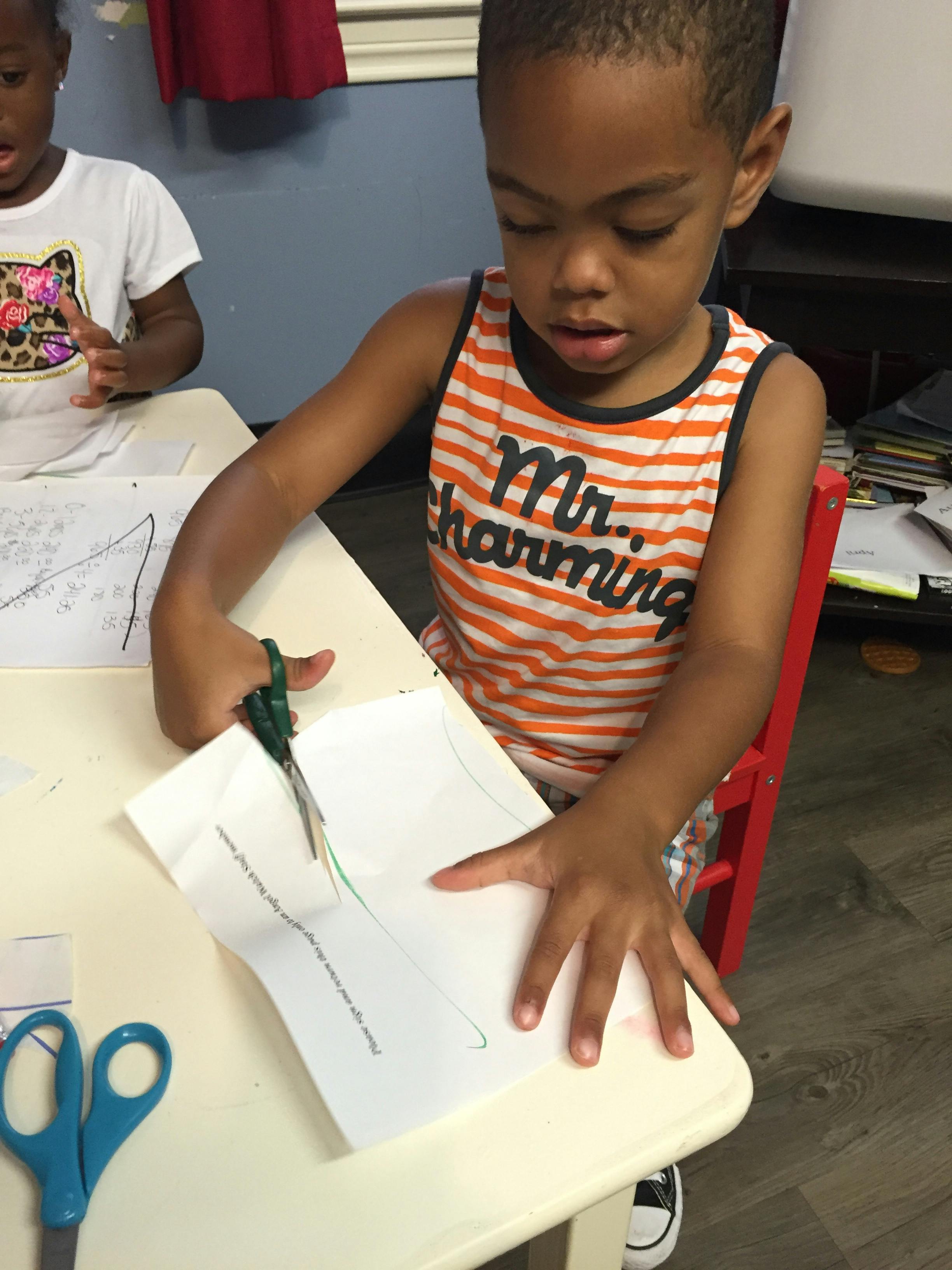 Child cutting paper with scissors at a desk
