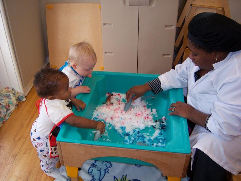 Adult and two children playing with foam in a sensory bin