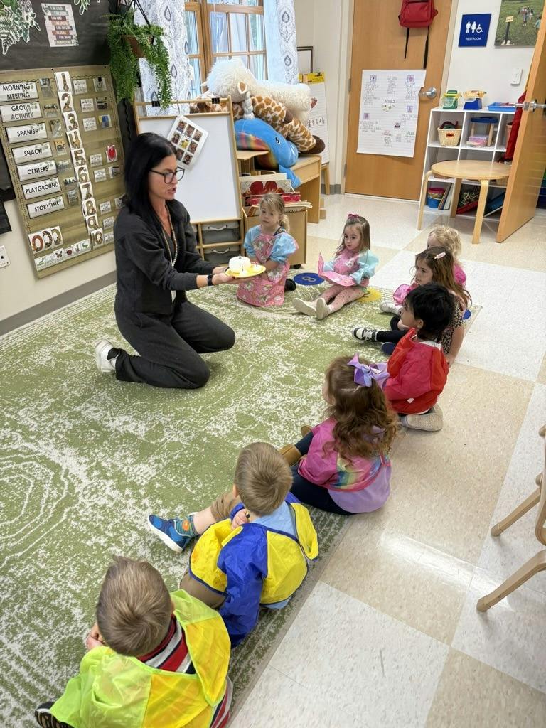 Teacher holding a small pumpkin for a group of children sitting in a classroom