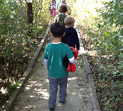 Children walking on a path in a wooded area
