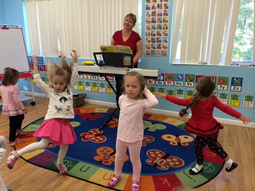 Adult playing keyboard for children dancing in a classroom
