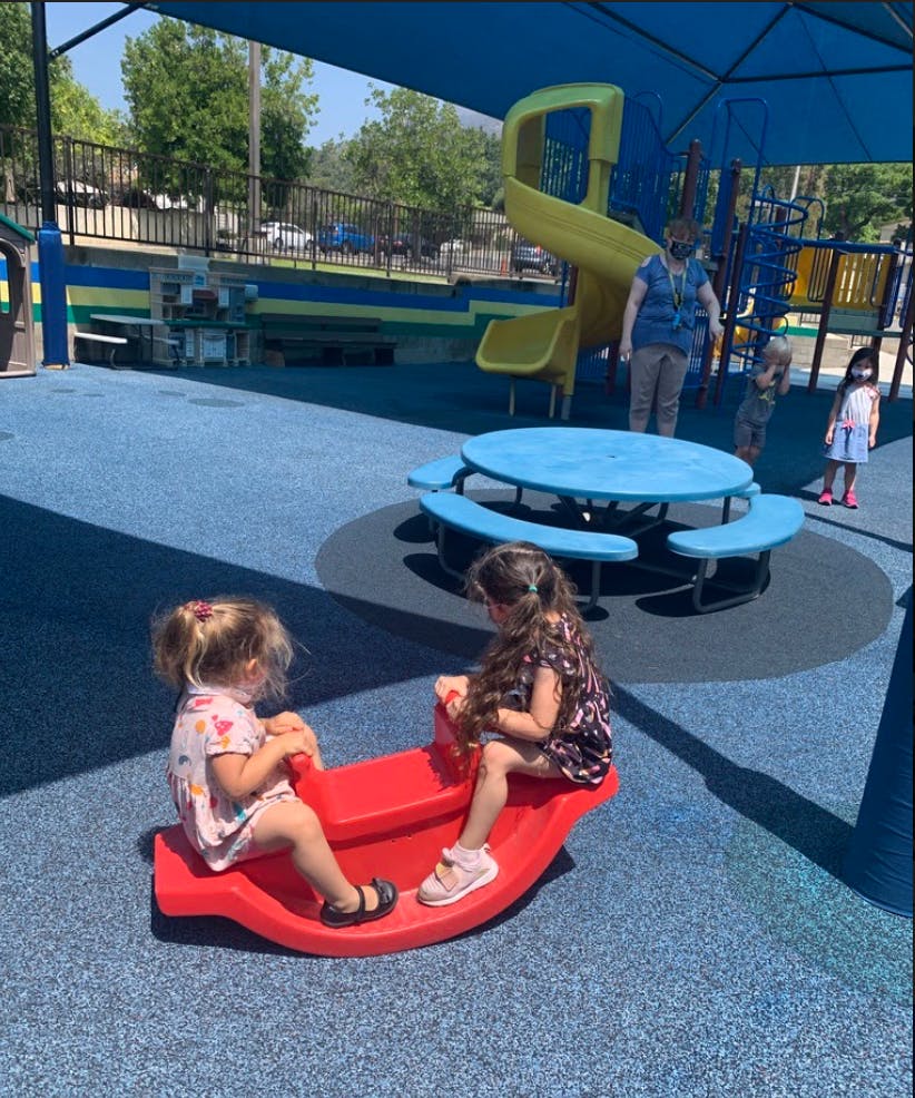 Two children on a red seesaw on a playground