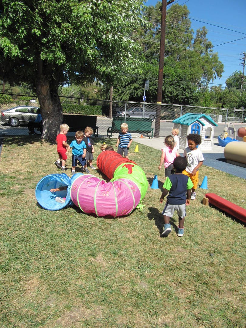 Children playing with colorful tunnels on a grassy area