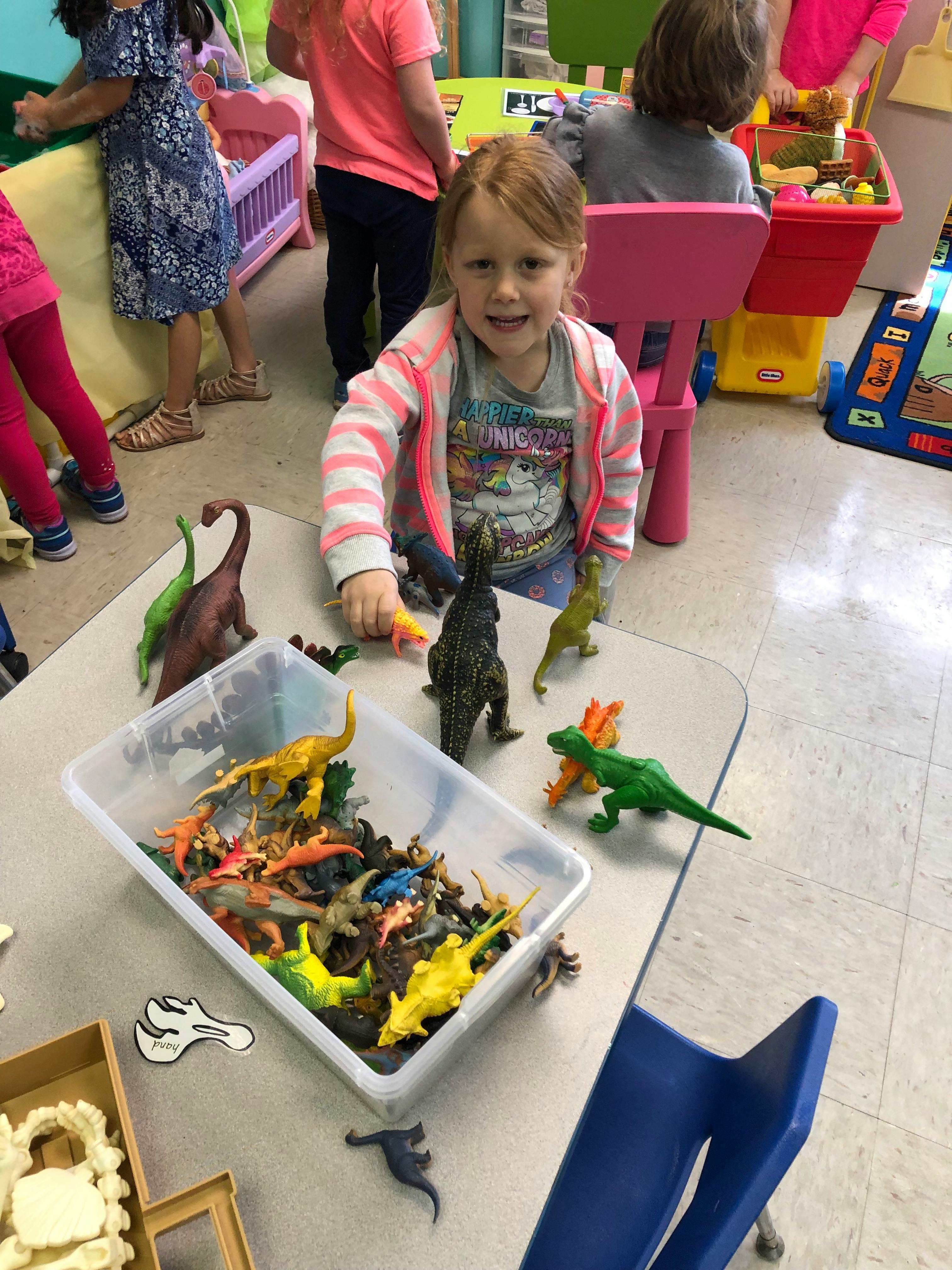 Child playing with dinosaur toys on a table