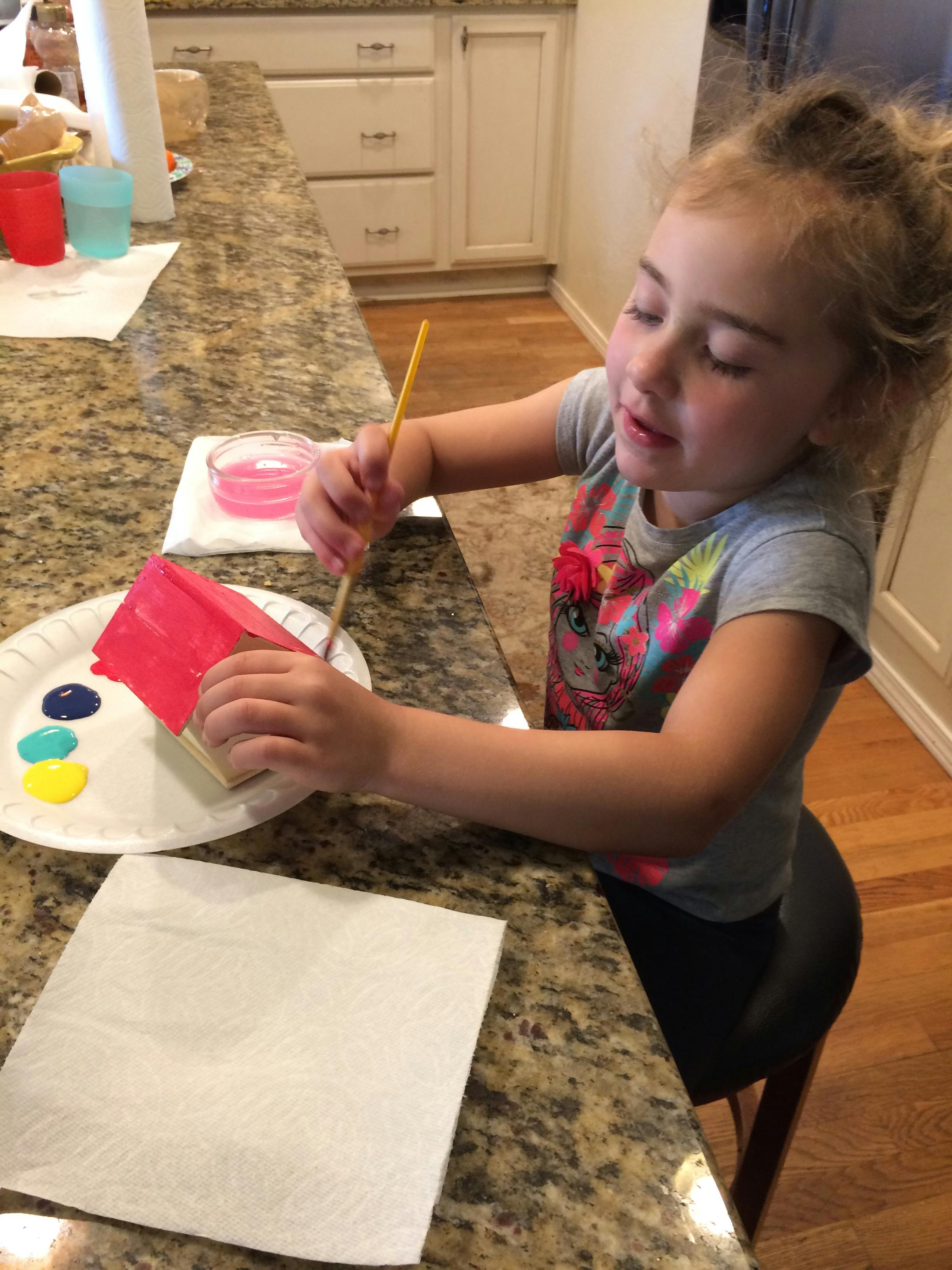 Child painting a small object with a paintbrush