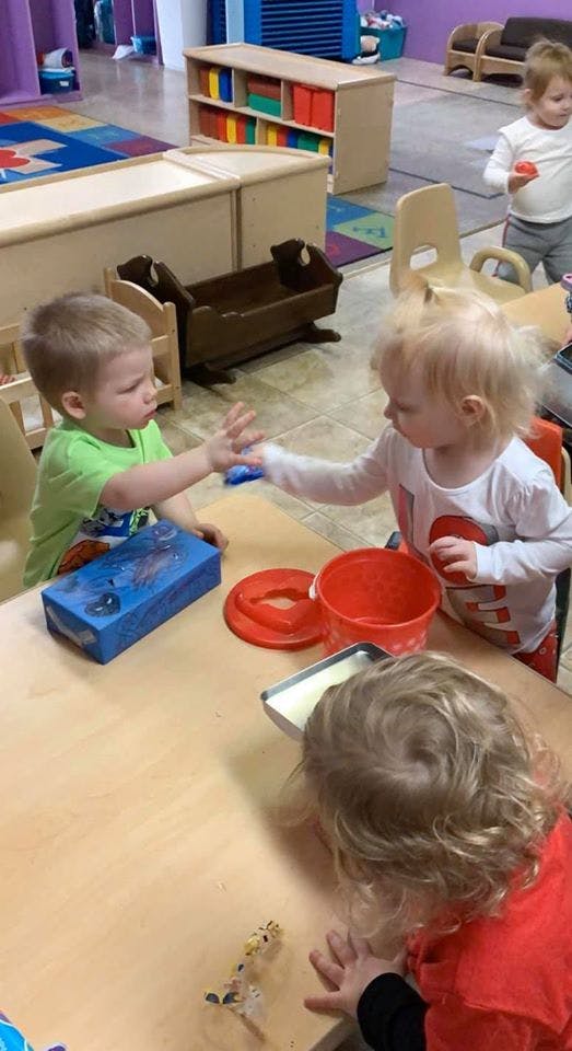 Two children playing with toys at a table