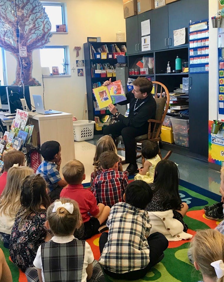 Person reading a book to a group of children in a classroom