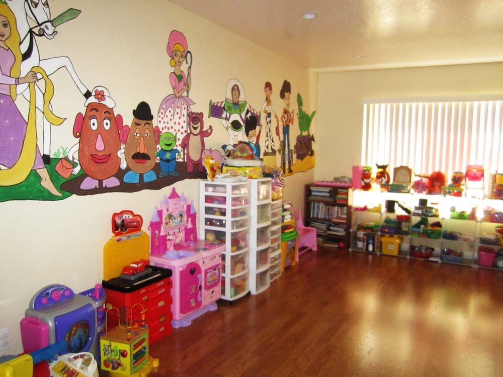 Playroom with cartoon character murals and various toys and storage units
