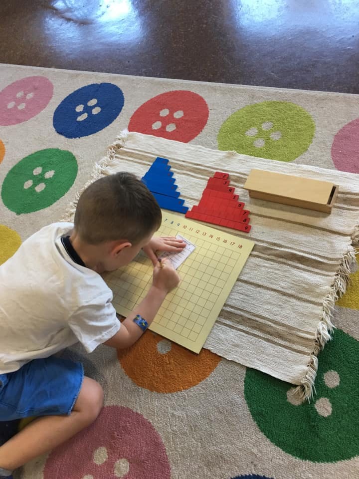 Child writing on a grid paper on the floor
