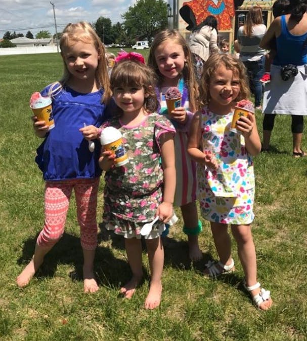 Four children holding cups of ice cream or shaved ice outdoors
