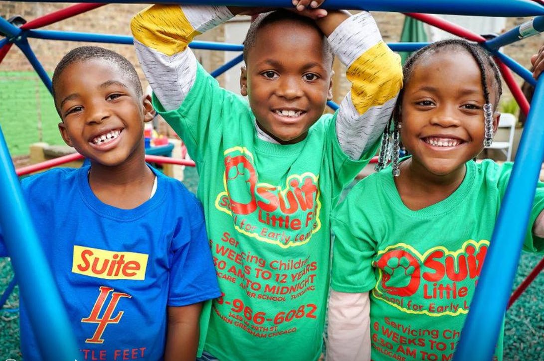 Three children smiling on a playground climbing structure