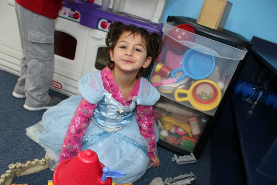Child in a blue dress kneeling on the floor