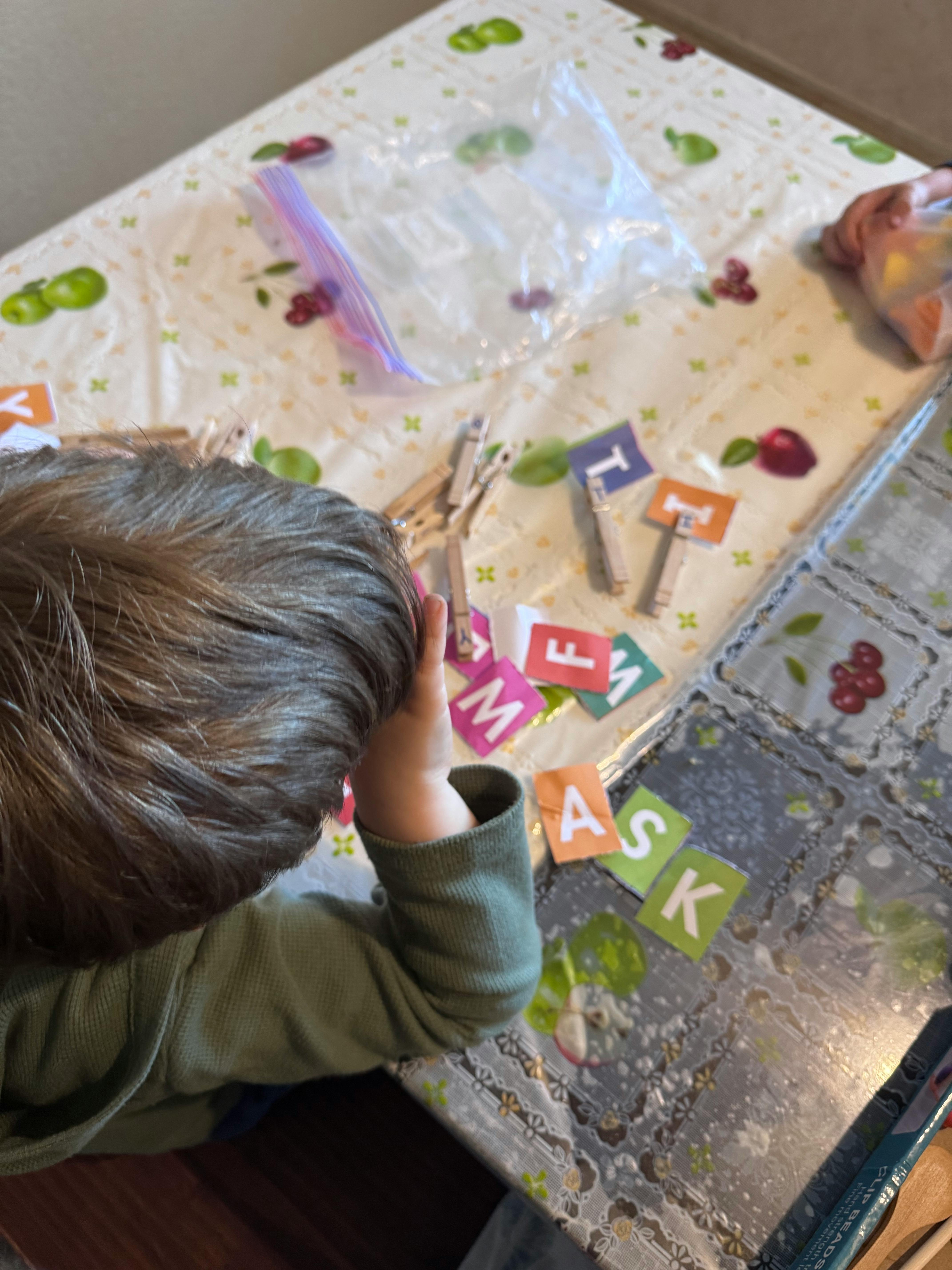 Child playing with letter tiles and clothespins on a table