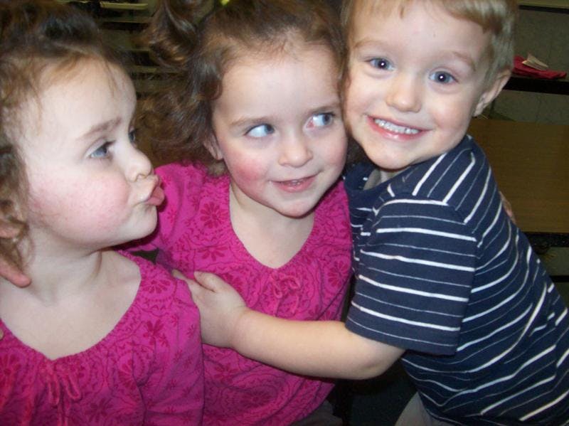 Three children posing together, one child puckering lips