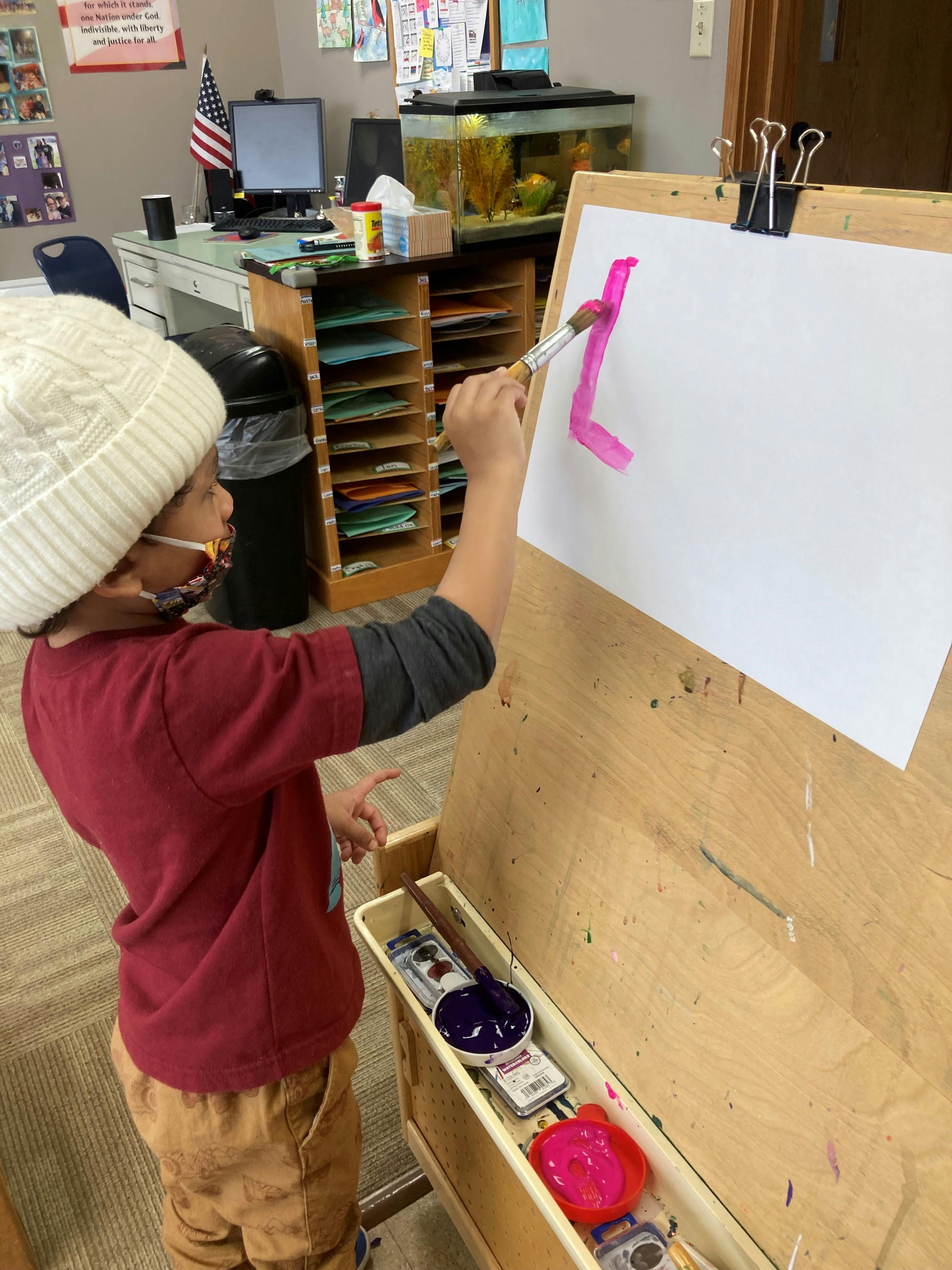 Child painting on an easel in a classroom