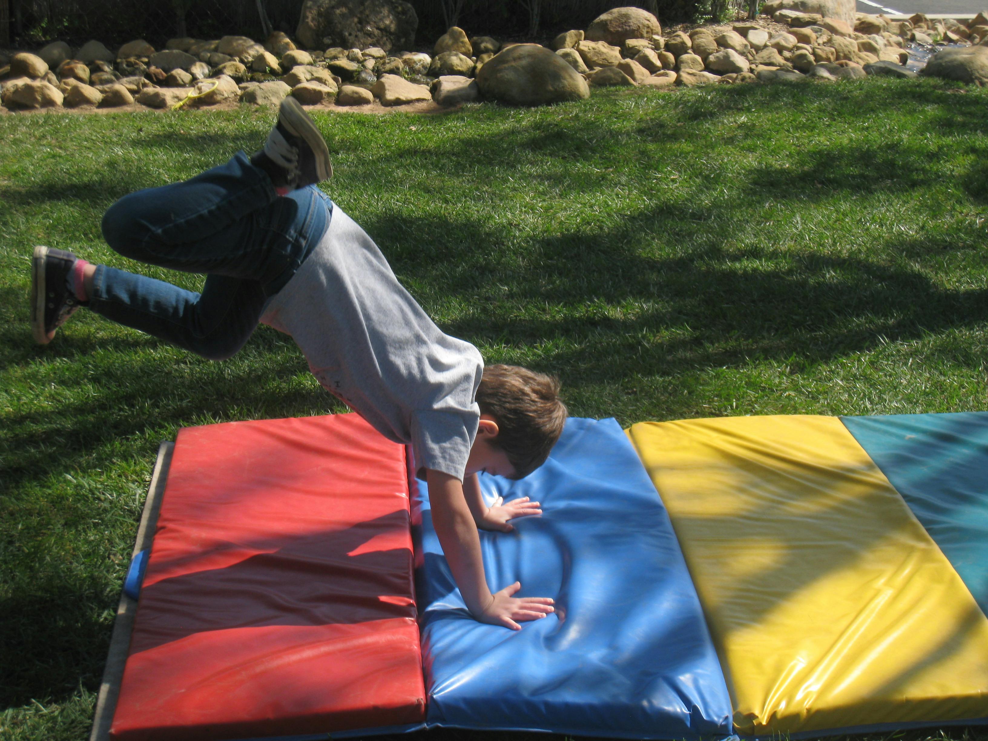 Child doing a handstand on colorful mats outdoors