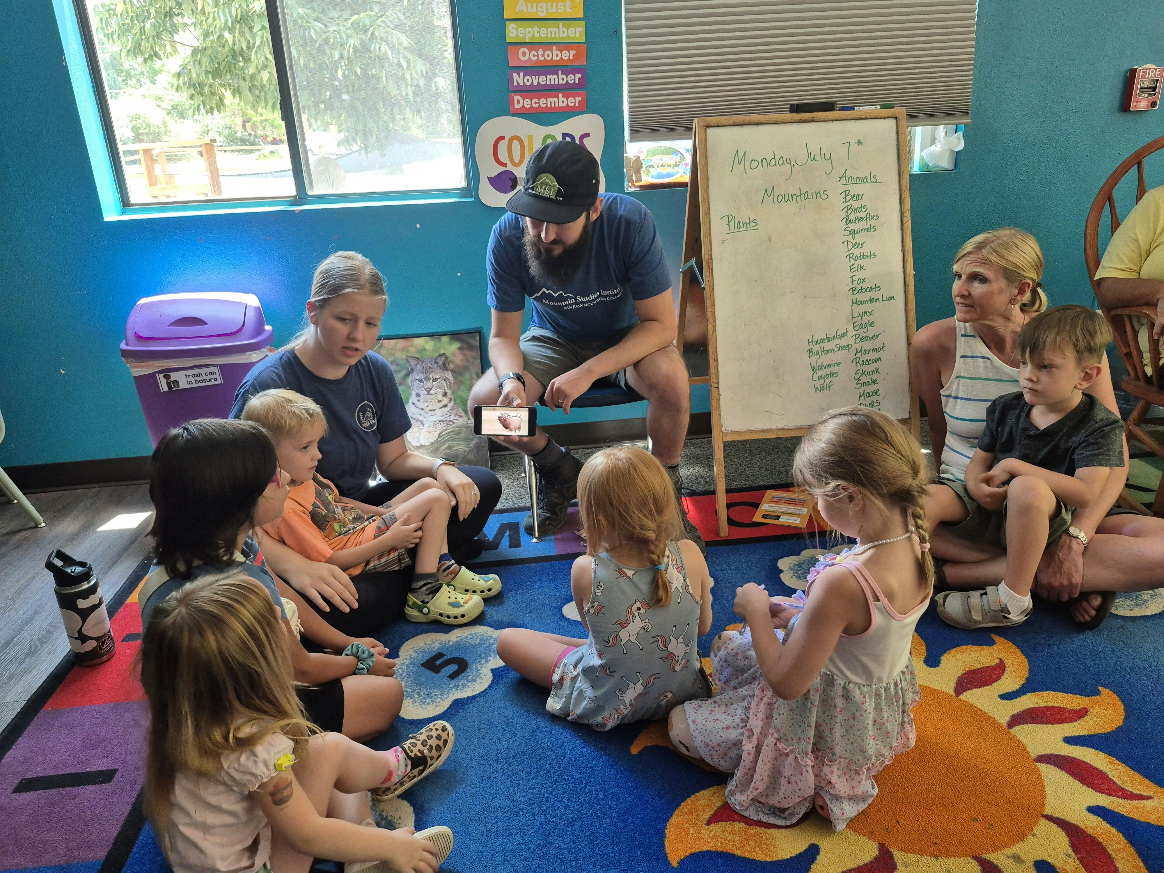 Adults and children sitting on a rug in a classroom