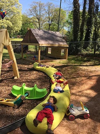 Children lying on a long yellow beanbag in a playground