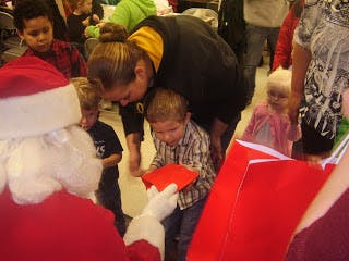 Person dressed as Santa Claus giving a gift to a child