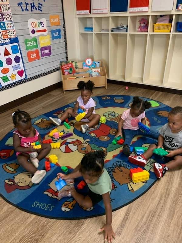 Children playing with blocks on a rug in a classroom
