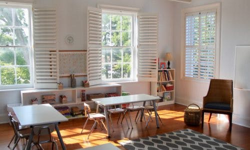 Classroom with tables, chairs, and windows with white shutters