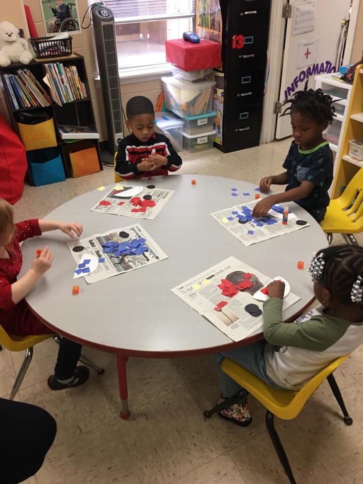 Children sitting at a round table doing crafts in-class activities