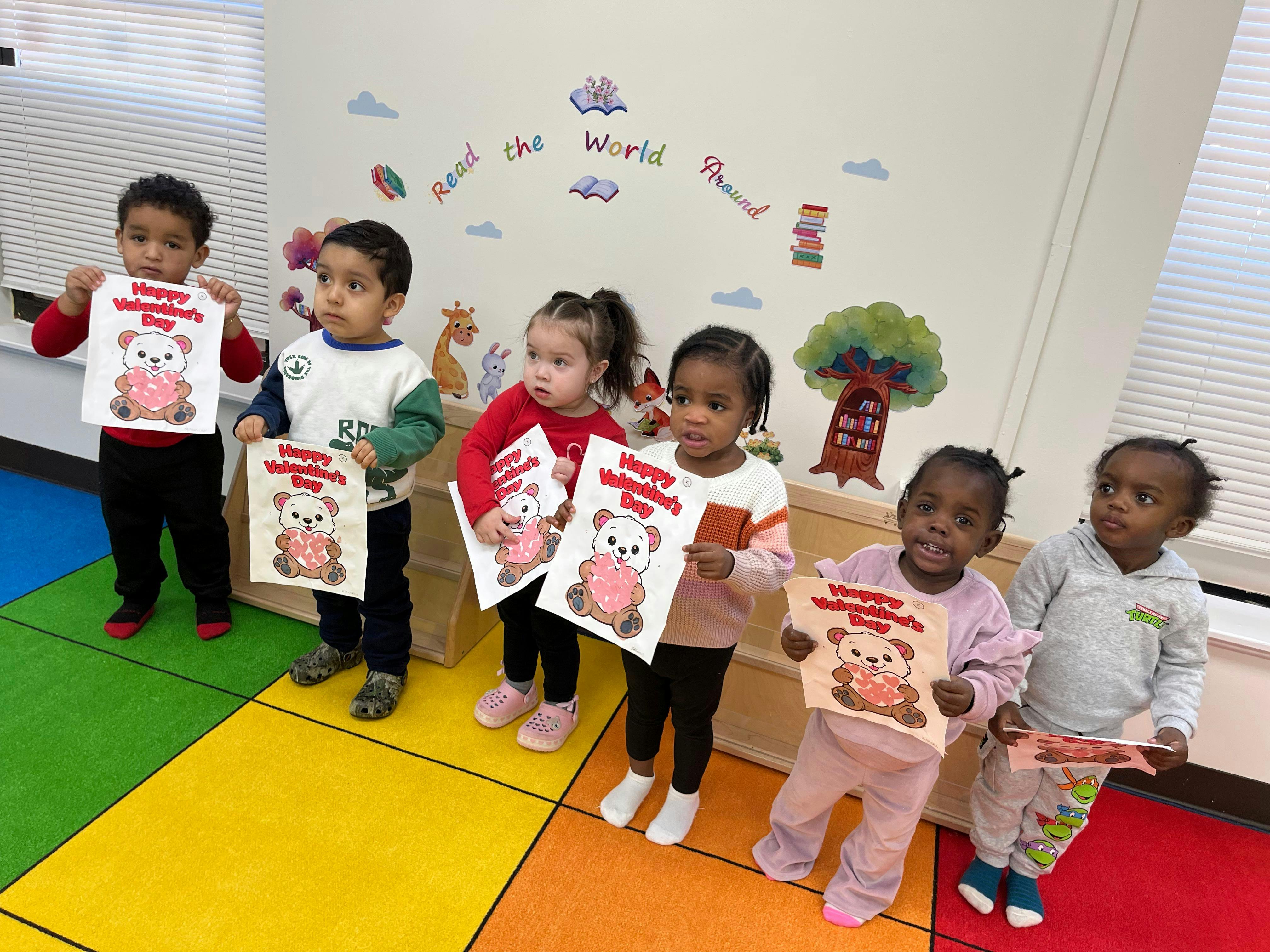 Group of children holding up signs that say "Happy Valentine's Day"