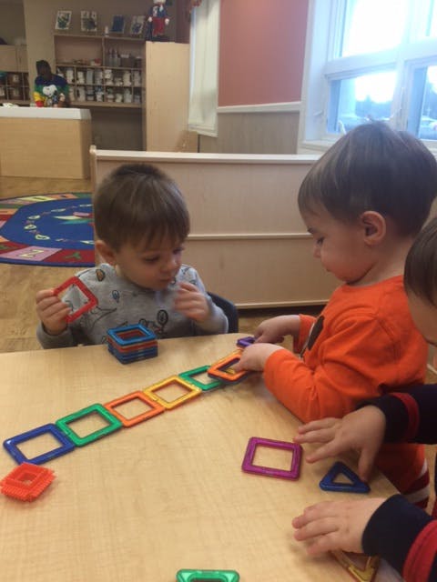Two children playing with colorful magnetic squares at a table