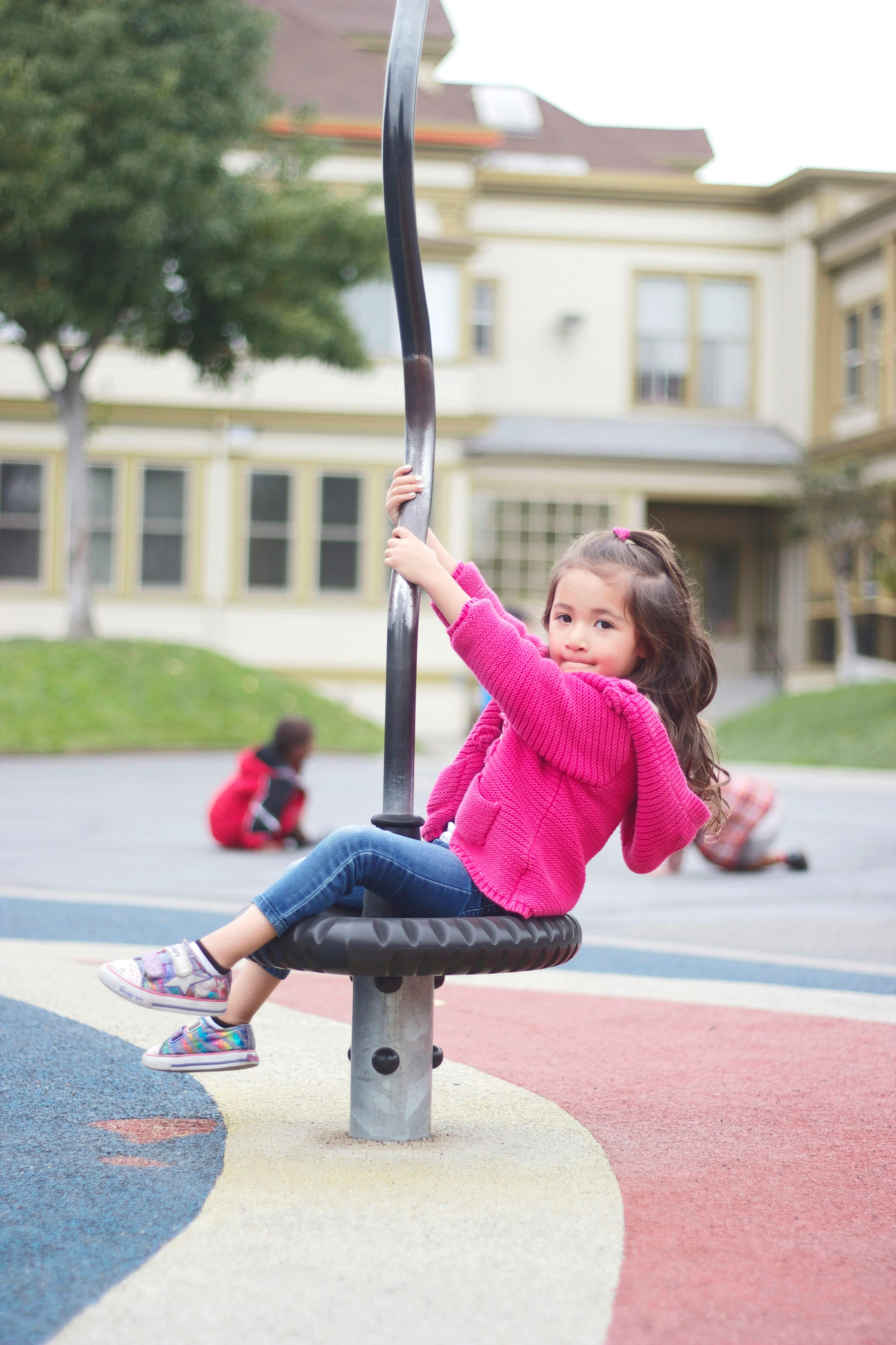 Child sitting on a playground spinner