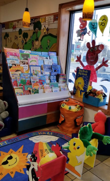 Children's book display with a colorful rug and stuffed animals