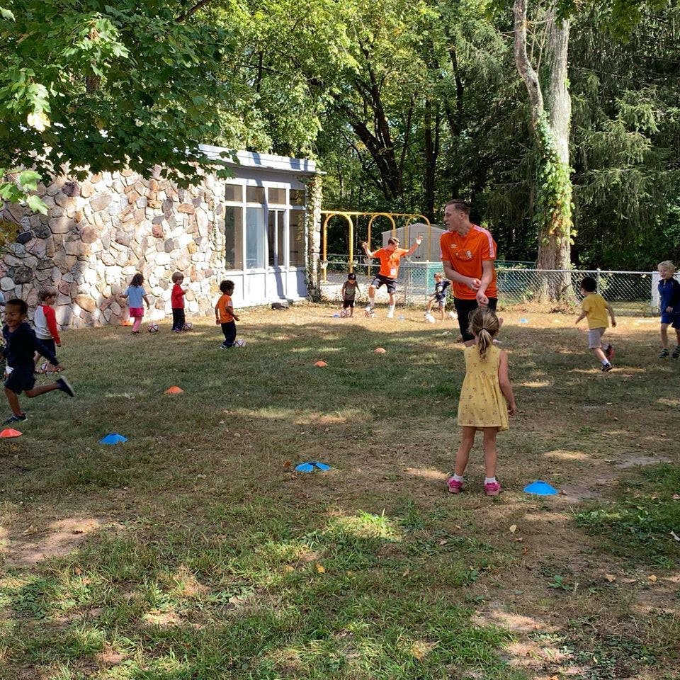 Adult and children playing outdoors on a grassy area