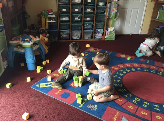 Two children playing with blocks on a rug in a classroom
